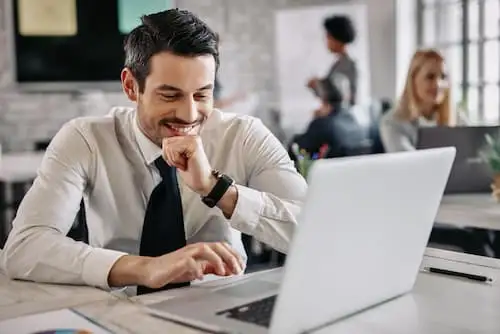 Profissional de gravata trabalhando em notebook em ambiente de escritório corporativo