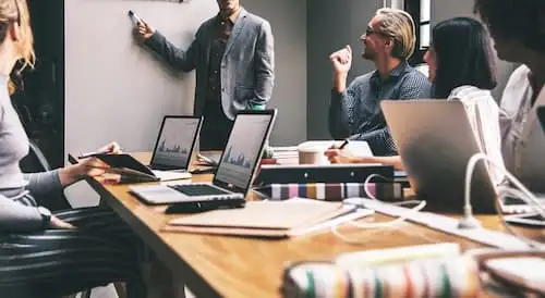 TCO Locação de TI Equipe em reunião com notebooks e gráficos na mesa avaliando TCO de locação de TI