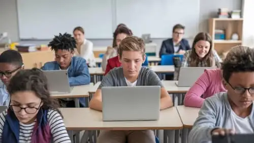 Alunos do ensino médio usando notebooks em sala de aula com professor ao fundo